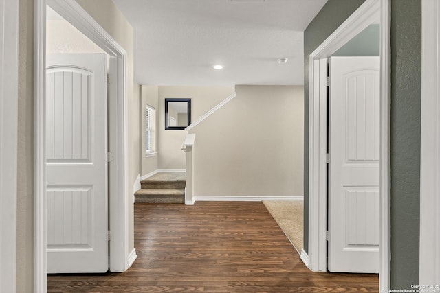 corridor featuring stairs, baseboards, and dark wood-style flooring