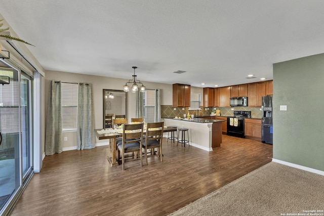 dining area featuring a chandelier, a healthy amount of sunlight, baseboards, and dark wood-style flooring