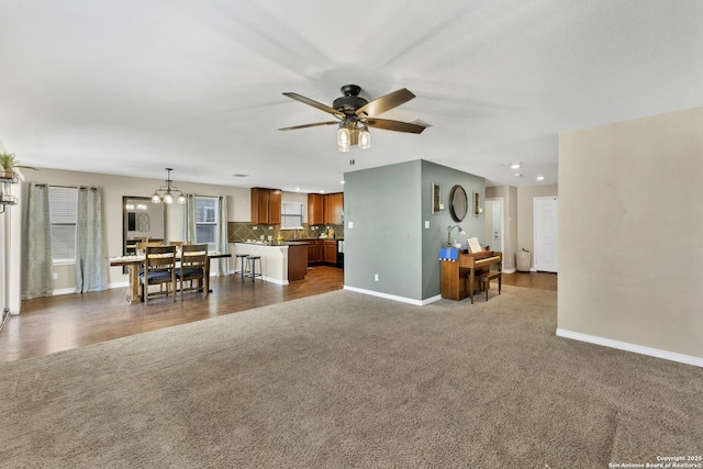 unfurnished living room with dark colored carpet, baseboards, and a ceiling fan