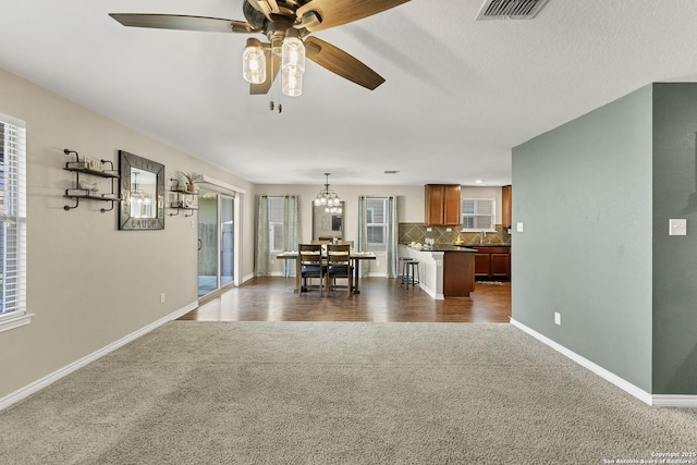 unfurnished living room featuring baseboards, visible vents, ceiling fan, a sink, and dark carpet