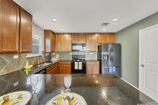 kitchen with visible vents, a sink, black appliances, brown cabinets, and backsplash