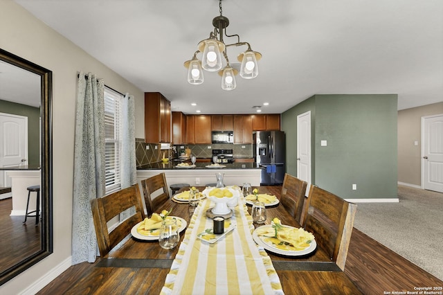 dining space featuring a chandelier, dark wood-type flooring, baseboards, and dark colored carpet