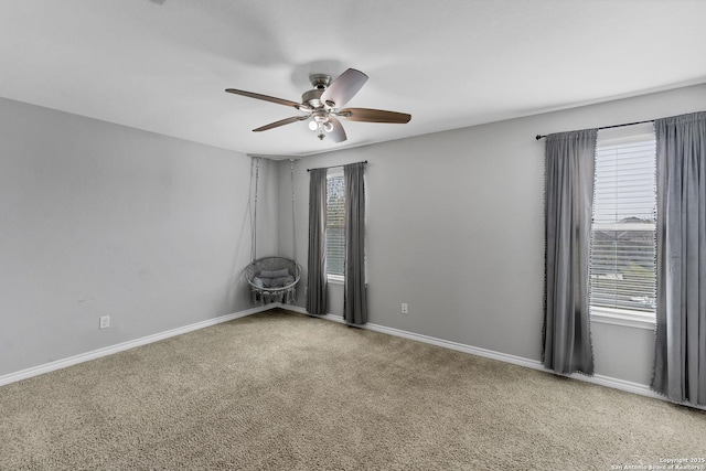 carpeted spare room with plenty of natural light, baseboards, and a ceiling fan