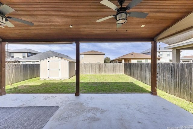 view of patio with a fenced backyard, ceiling fan, a storage unit, and an outdoor structure