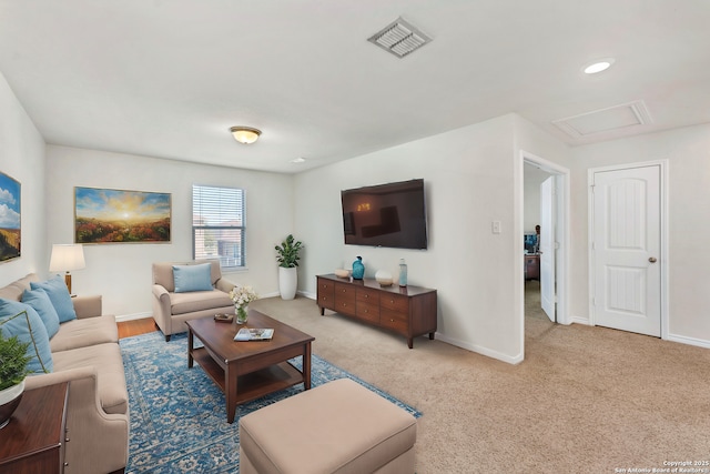 living area featuring visible vents, baseboards, attic access, and light carpet