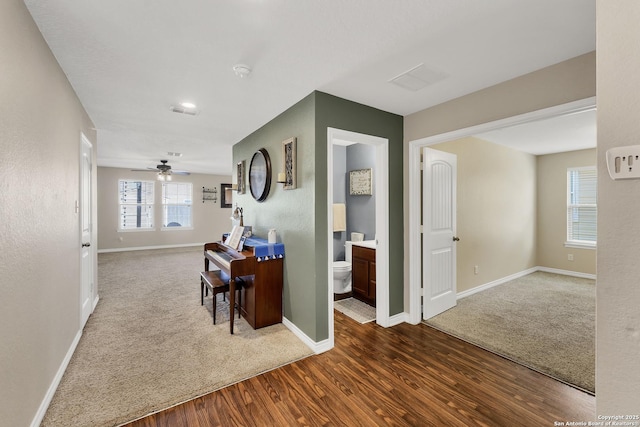 hall featuring carpet flooring, baseboards, and wood finished floors