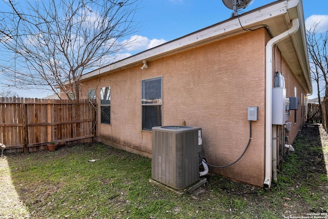 view of property exterior with cooling unit, fence, a lawn, and stucco siding