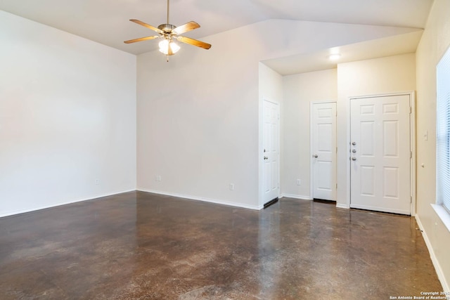 spare room featuring baseboards, lofted ceiling, concrete flooring, and a ceiling fan