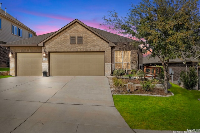 view of front of home with a yard, stone siding, concrete driveway, and a garage