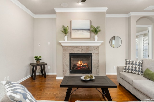 living area with crown molding, wood finished floors, baseboards, and a premium fireplace