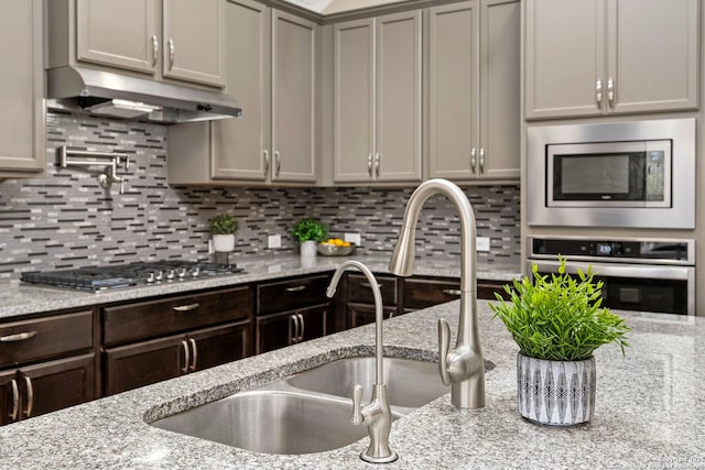 kitchen with under cabinet range hood, appliances with stainless steel finishes, and tasteful backsplash