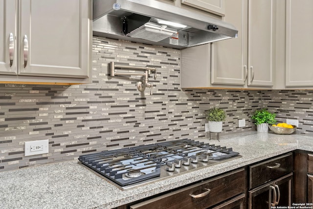 kitchen featuring decorative backsplash, dark brown cabinets, under cabinet range hood, and stainless steel gas cooktop