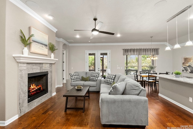 living room featuring baseboards, a tiled fireplace, ornamental molding, french doors, and dark wood-style flooring