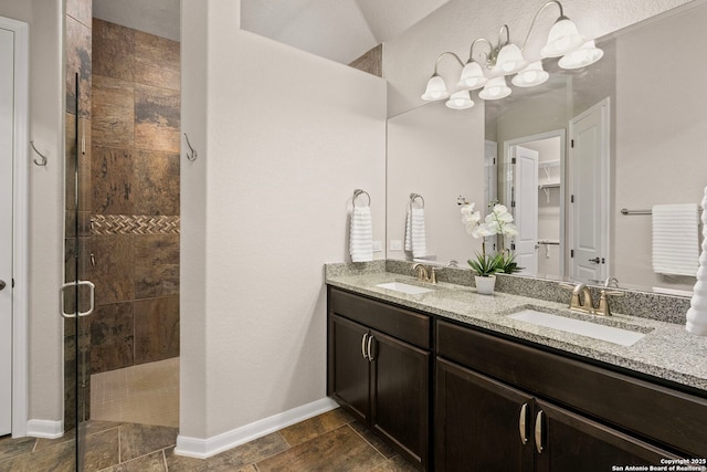 bathroom featuring a sink, baseboards, a stall shower, and double vanity