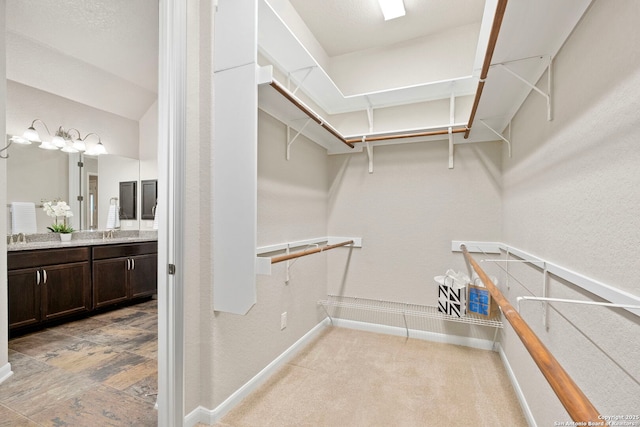 walk in closet featuring a sink and light carpet