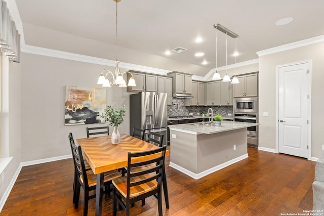 kitchen featuring tasteful backsplash, gray cabinets, appliances with stainless steel finishes, and dark wood-type flooring