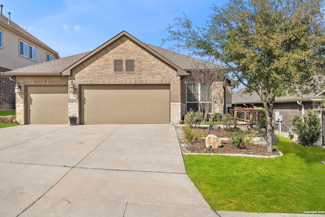 view of front of house featuring a front yard, roof with shingles, driveway, stone siding, and an attached garage