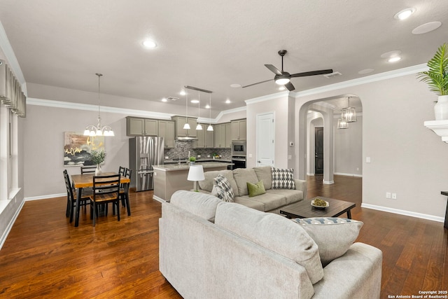 living room with baseboards, visible vents, arched walkways, dark wood-type flooring, and ceiling fan with notable chandelier