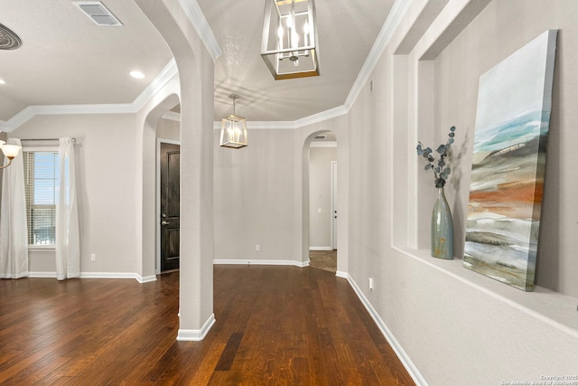 foyer featuring baseboards, visible vents, arched walkways, ornamental molding, and hardwood / wood-style flooring