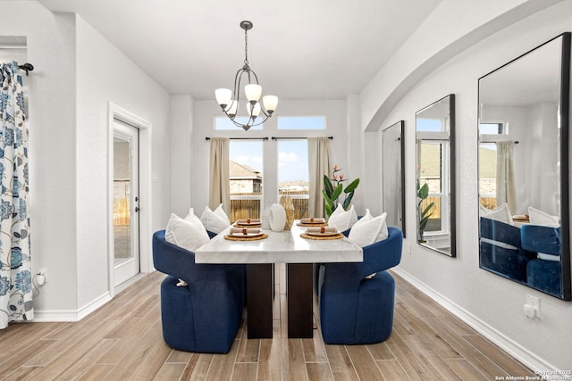 dining space featuring an inviting chandelier, baseboards, and wood tiled floor