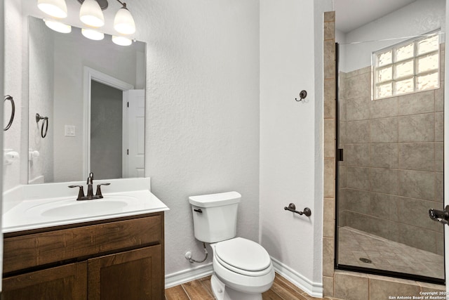 bathroom featuring a shower stall, toilet, vanity, and wood finished floors