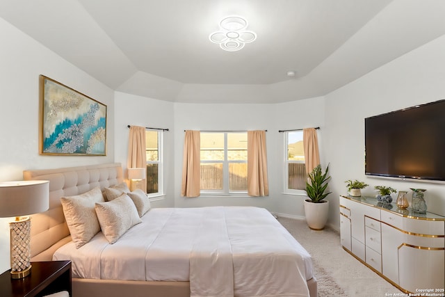 bedroom featuring a tray ceiling, baseboards, and light carpet