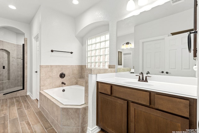 bathroom featuring vanity, wood tiled floor, recessed lighting, a shower stall, and a bath