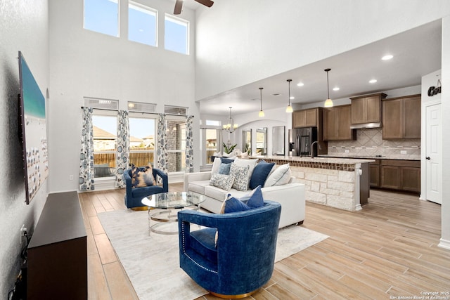 living room featuring a wealth of natural light, ceiling fan with notable chandelier, recessed lighting, and light wood finished floors