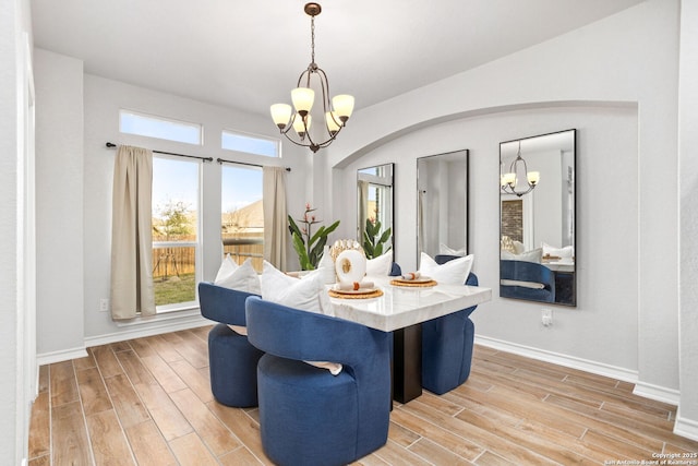 dining room with breakfast area, light wood-style floors, and an inviting chandelier