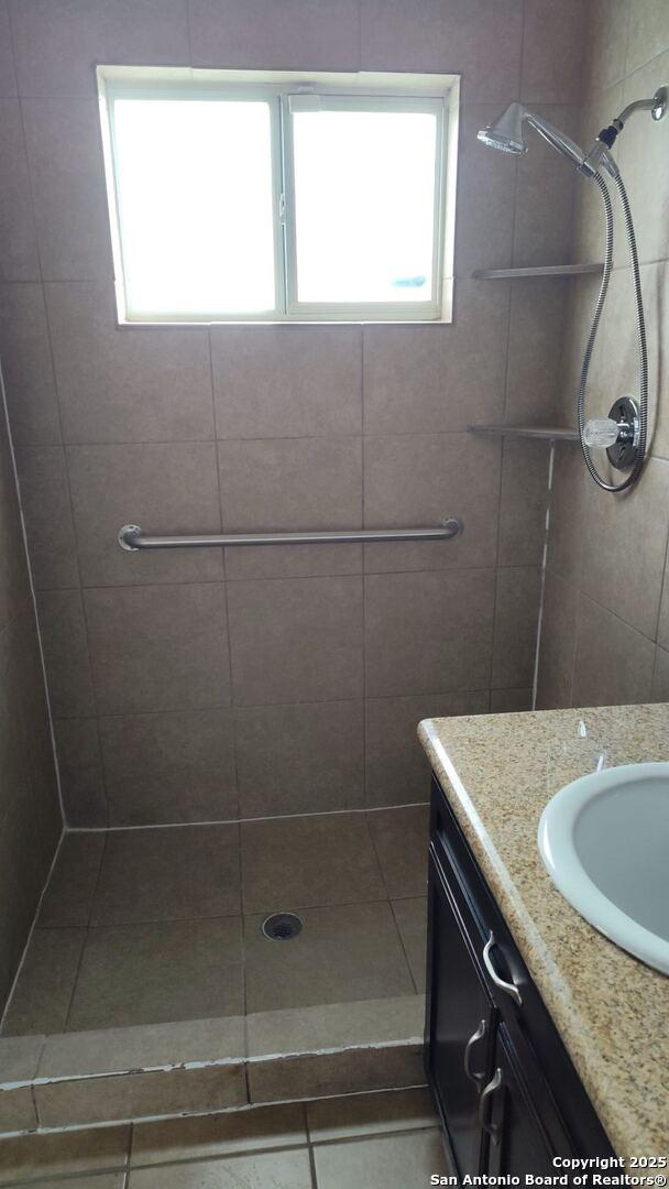 full bath with vanity and a tile shower