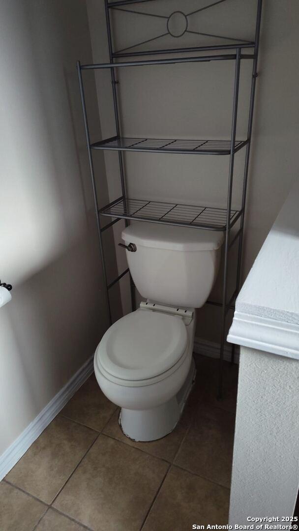 bathroom with tile patterned floors, toilet, and baseboards