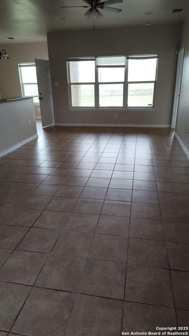 unfurnished room with tile patterned flooring, plenty of natural light, baseboards, and visible vents