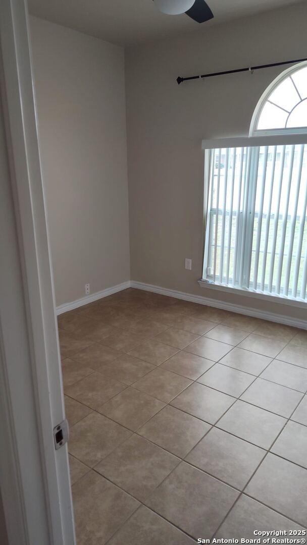 unfurnished room with light tile patterned floors, a healthy amount of sunlight, baseboards, and ceiling fan