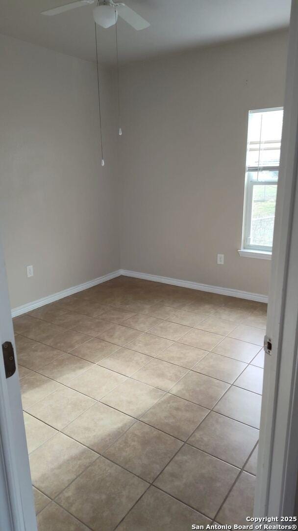 spare room featuring light tile patterned floors, a ceiling fan, and baseboards