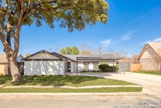 ranch-style house featuring fence, concrete driveway, a front yard, a carport, and solar panels