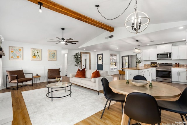 dining space with ceiling fan with notable chandelier, vaulted ceiling with beams, light wood-style floors, and visible vents