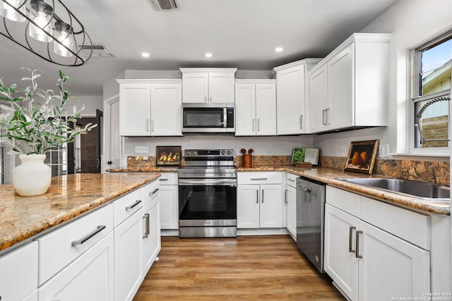 kitchen featuring light wood-type flooring, a sink, white cabinetry, recessed lighting, and appliances with stainless steel finishes