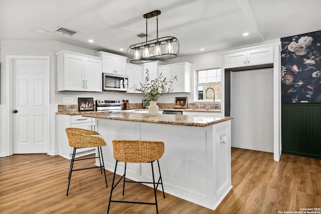 kitchen featuring white cabinetry, visible vents, appliances with stainless steel finishes, and a center island