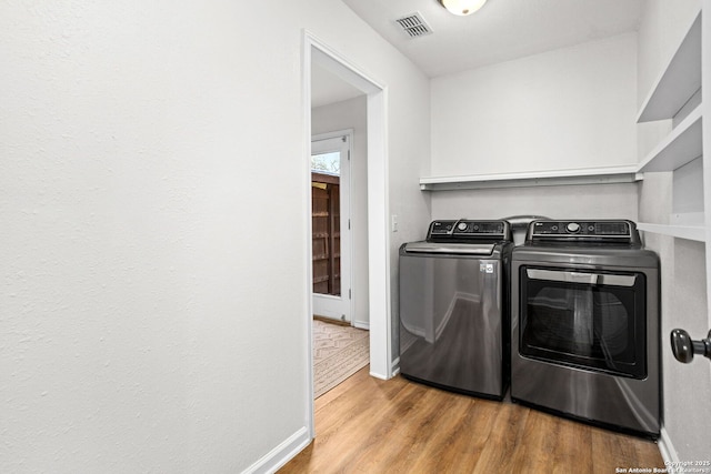 laundry room featuring wood finished floors, baseboards, visible vents, laundry area, and washer and clothes dryer