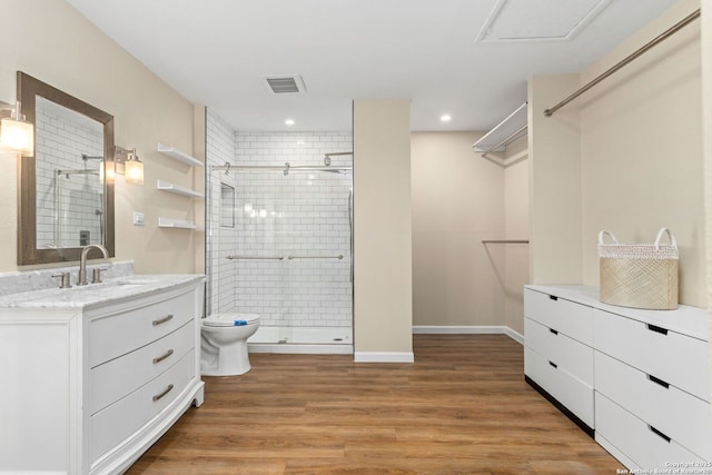 bathroom with vanity, wood finished floors, visible vents, a stall shower, and toilet