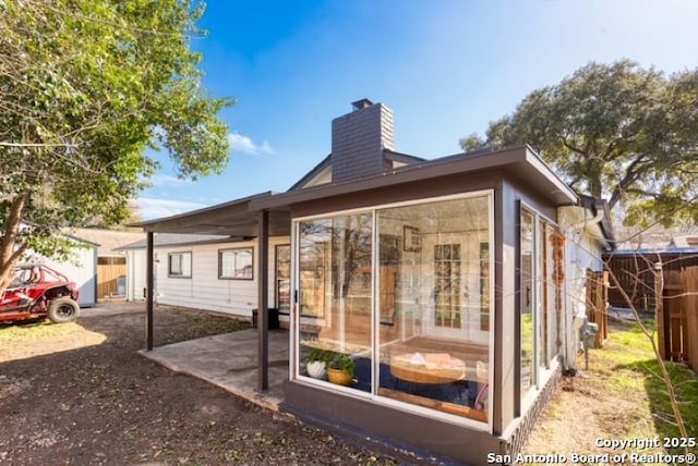 view of outdoor structure featuring fence and a sunroom