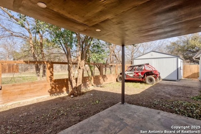 view of yard featuring an outdoor structure, a fenced backyard, a shed, and a patio