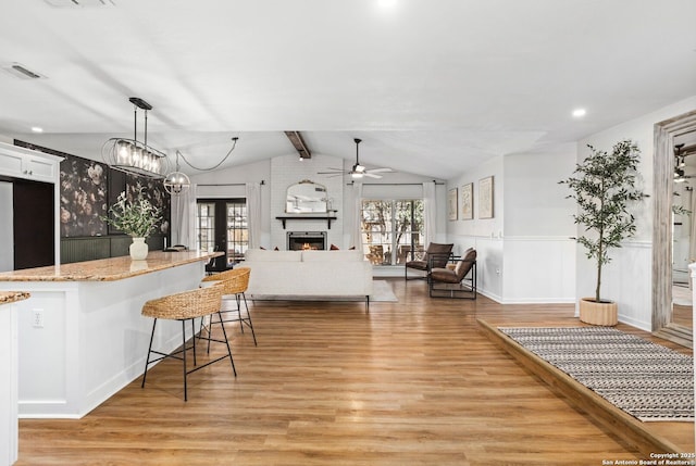 kitchen featuring a breakfast bar, light wood-style flooring, vaulted ceiling with beams, and visible vents