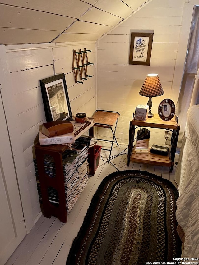 hallway featuring hardwood / wood-style flooring, wooden walls, and lofted ceiling