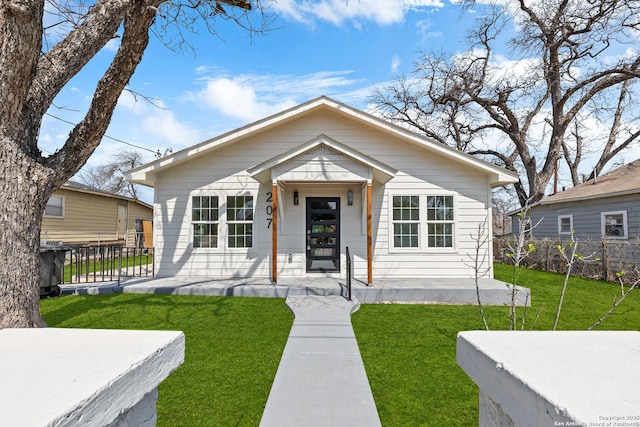 bungalow-style home with a front lawn and fence