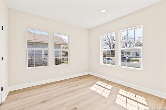 empty room featuring recessed lighting, a healthy amount of sunlight, light wood-type flooring, and baseboards