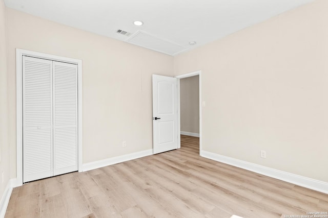 unfurnished bedroom featuring visible vents, baseboards, attic access, and wood finished floors