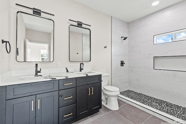 bathroom with toilet, a sink, tile patterned flooring, double vanity, and tiled shower