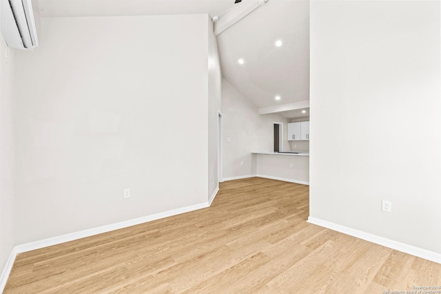 unfurnished living room with light wood finished floors, beam ceiling, an AC wall unit, and baseboards