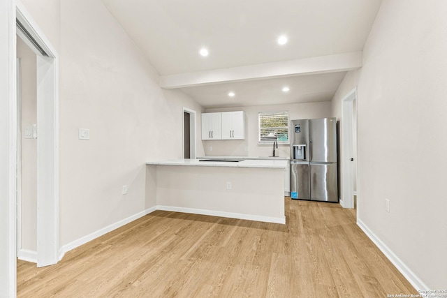 kitchen featuring baseboards, light countertops, stainless steel refrigerator with ice dispenser, beamed ceiling, and light wood-type flooring